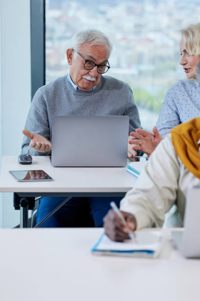 istock A senior man is smiling while having a retraining class with a multicultural group of senior people in the classroom. 1408386464