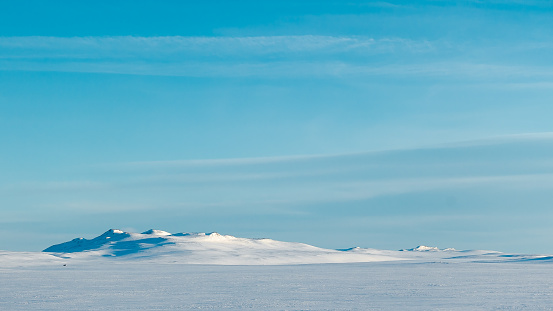 Low hills is a snowy landscape under a clear blue sky
