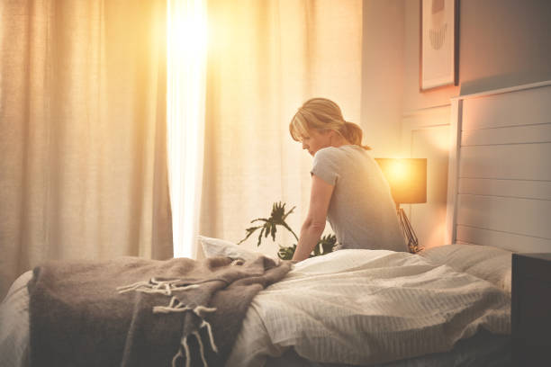 Depressed lonely mature woman waking up early in the morning, thinking, sitting in bed. Divorced, anxious, suffering from chronic insomnia, sleep apnea, mental health disorder. Feeling sad, confused stock photo