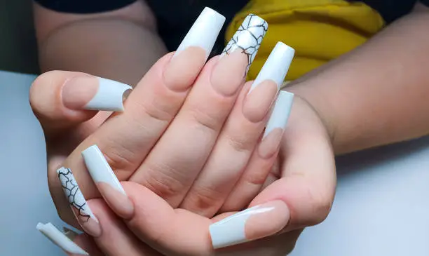 Photo of Acrylic nail extension. Manicure. Nail correction. Hands in the foreground.