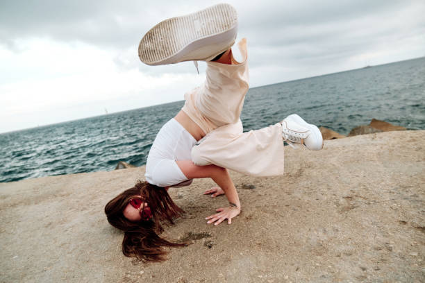 istock Female dancer doing handstand while breakdancing outdoors against sea. 1408391025