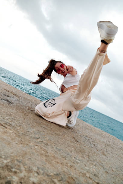 istock Female hip-hop dancer smiling while making a freestyle dance pose against sea. 1408391114