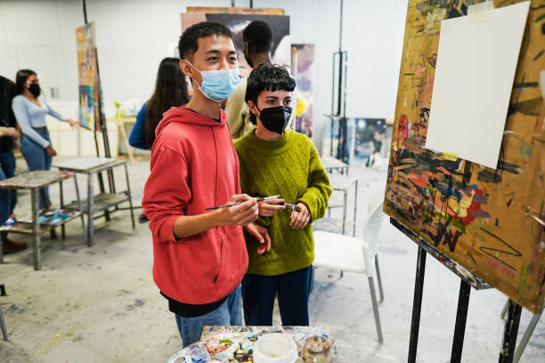 istock Multiracial students painting inside art room class wearing safety masks 1408391797