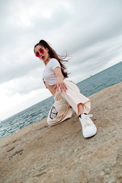 istock Female dancer looking at camera while making a pose outdoors against the sea. 1408391967