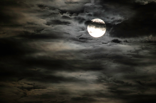 Image of bright full moon in dark sky with dramatic of light and texture on soft cloudscape in black and white for meteorology background.