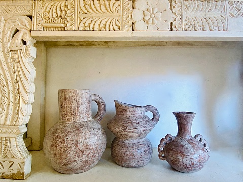 Horizontal still life of ceramic earthenware pots placed on white floor under wood carved seat bench in public retail store