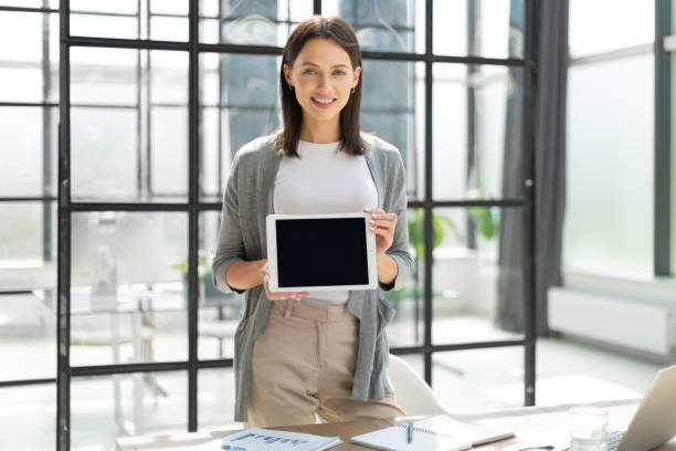 istock Young happy business woman showing blank tablet computer screen in office 1408393378