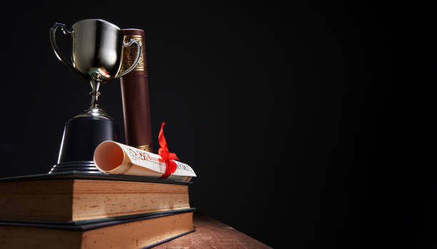 gold trophy with scroll of certificate against black background