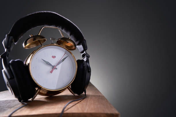 antique alarm clock with earphone against gray background