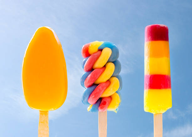 Three colourful ice-lollies in a row against a blue sky
