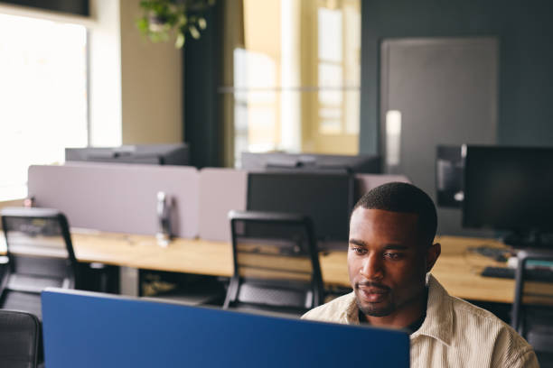 istock Young black man working on computer in modern office at desk 1408397207