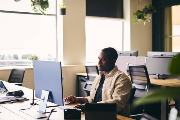 istock Young black man working on computer in modern office at desk 1408397212