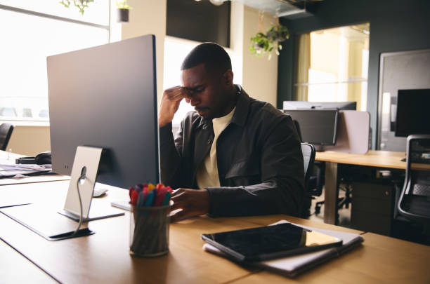 istock Stressed black businessman sat at office desk with mental illness 1408397236