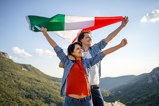 Happy couple holding Italian national flag on top of the hill