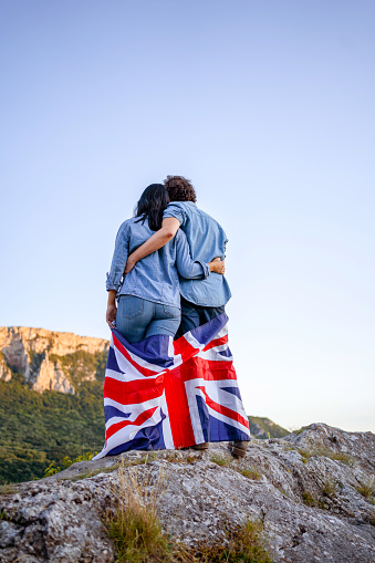 Happy couple holding national flag of United Kingdom on top of the hill