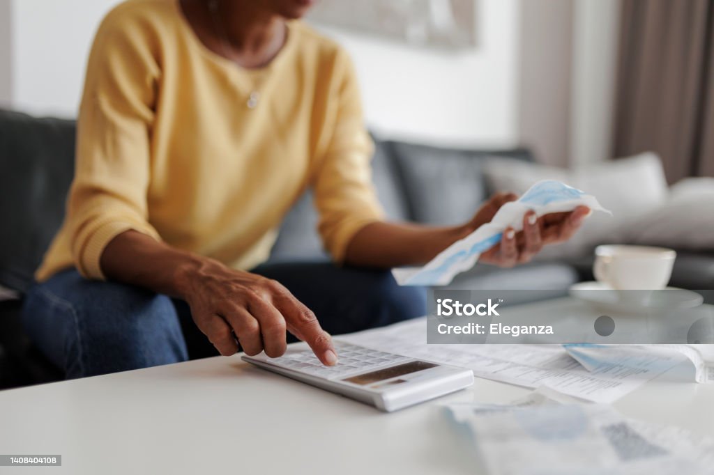 Close up of a mid adult woman checking her energy bills at home, sitting in her living room. She has a worried expression Inflation - Economics Stock Photo
