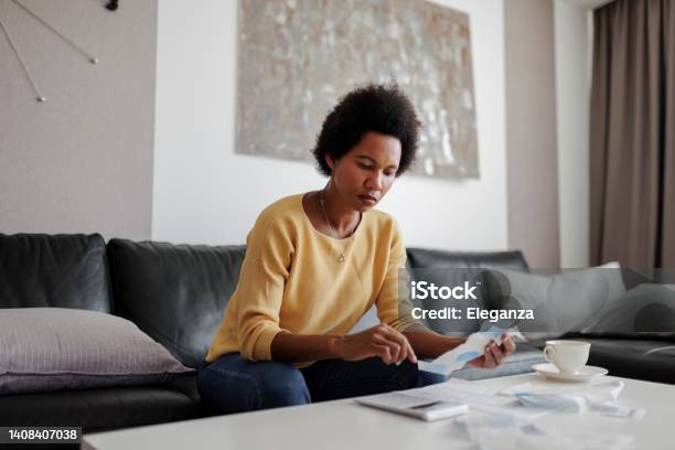 Portrait Of A Mid Adult Woman Checking Her Energy Bills At Home Sitting In Her Living Room She Has A Worried Expression Stock Photo - Download Image Now