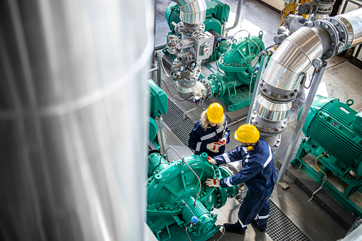 Trabajadores industriales de gas y petróleo trabajando juntos y revisando las bombas de tuberías y motores en la fábrica. photo
