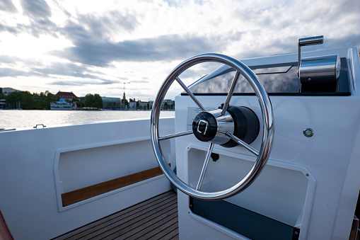 Round metal steering wheel of a small electric rental boat. Sunny summer day, no people.