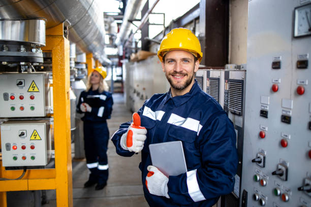 Portrait of factory worker holding thumbs up in petrochemical industrial refinery. stock photo