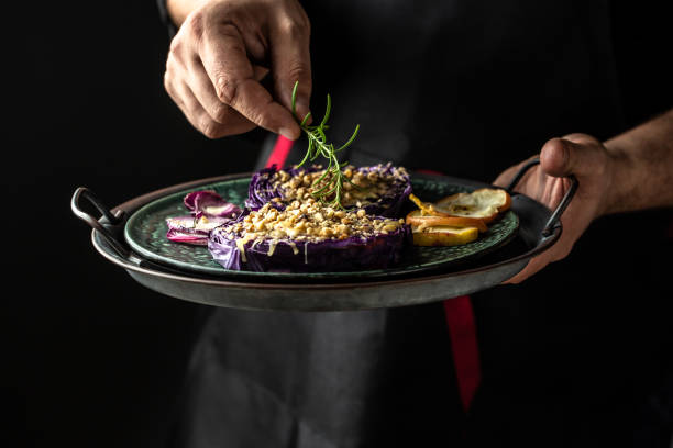 istock Chef finishing her plate. Only hands. Finally dish dressing red cabbage baked with nuts, quince and apples adds a sprig of fresh rosemary 1408411205