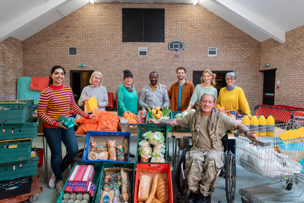 Supporting their Community Group of volunteers posting for a picture together alongside all of their food donations they have organised for a food bank in the North East of England. They are a diverse group and are all smiling, looking at the camera. Senior Volunteering: Making a Difference at Any Age stock pictures, royalty-free photos & images