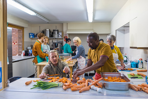 Volunteers working in a soup kitchen/food bank laughing together, preparing food. They are in the North East of England.