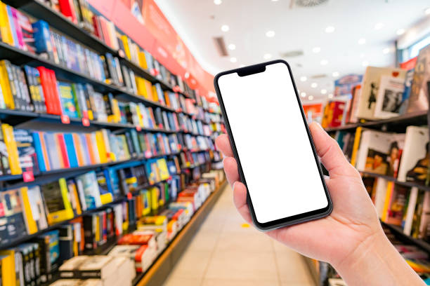 istock Hand holding mockup smartphone in a blurred bookstore interior 1408412926
