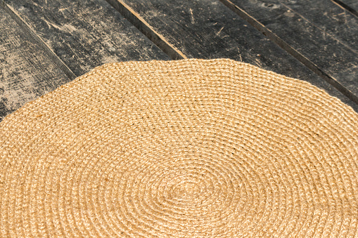handmade rug made of jute lies on the black wooden floor at the entrance to the house. closeup