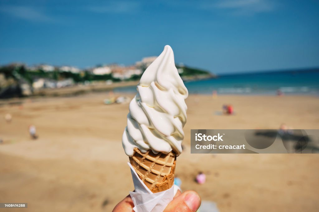 Hand holding an Ice Cream at Town Beach, Newquay, Cornwall on a sunny June day. Personal Perspective Stock Photo