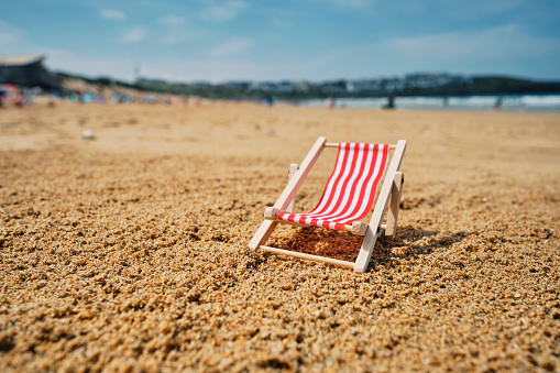 Red miniature wooden deck chair at Fistral beach, Newquay, Cornwall on a sunn y June day.