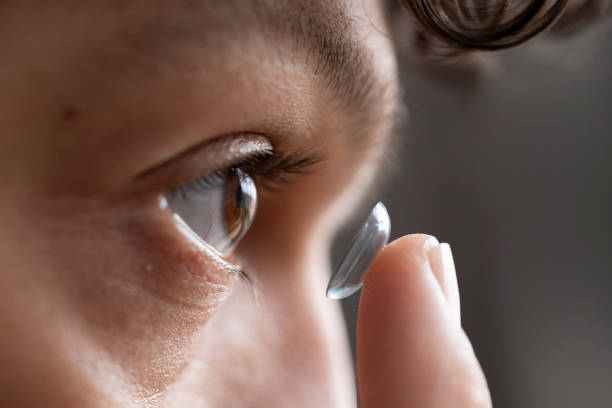 Close up of Young Male Adult Putting in Contact Lens Extreme close up of a young male adult holding a contact lens getting ready to insert into his eye with his finger. contact lens photos stock pictures, royalty-free photos & images