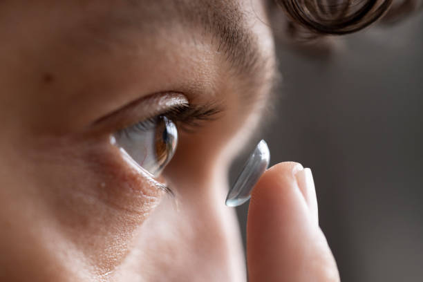 Close up of Young Male Adult Putting in Contact Lens Extreme close up of a young male adult holding a contact lens getting ready to insert into his eye with his finger. contact lens stock pictures, royalty-free photos & images