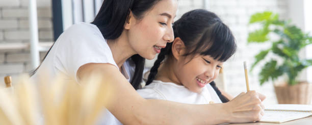 Mother teach homework to daughter learning online concept at home during lockdown from Coronavirus or covid-19 stock photo