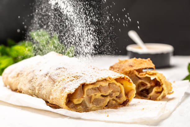 Strudel with pears with raisins and mint sieve sprinkling sugar powder from above. on light background. copy space Strudel with pears with raisins and mint sieve sprinkling sugar powder from above. on light background. copy space. strudel stock pictures, royalty-free photos & images