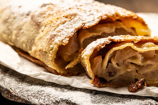 A Viennese Strudel apple powdered sugar on light background, classic and probably the best known Viennese pastry outside of Austria. Food recipe background. Close up.