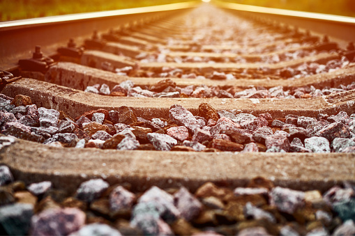 Railway track line in sunlight, beautiful train track landscape. Railroad with ballast gravel, rails and crushed stone. Industrial railway network for cargo delivery to railway station