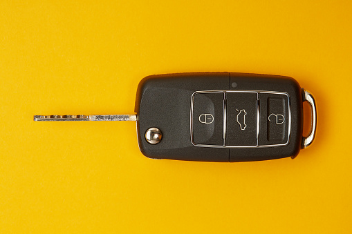Car key with remote control to lock or unlock the car and open the car trunk on yellow background