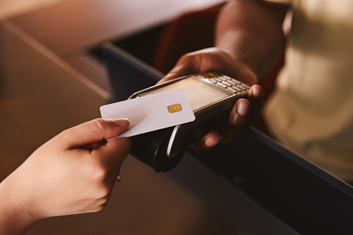 Cierre de asistente de ventas en tienda minorista con cliente que paga con tarjeta de crédito de pago sin contacto NFC photo