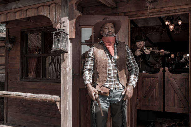 istock Handsome Black Cowboy with a priest in an authentic wild west setting 1408418275