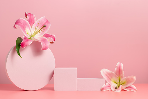 Geometric podium with lily flowers on pink background