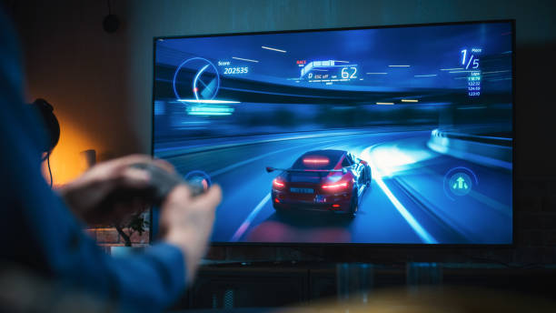 close up on man's hands at home, sitting on a couch in stylish loft apartment and playing arcade car video games on console. male using controller to play street racing drift simulator. - gamepad imagens e fotografias de stock