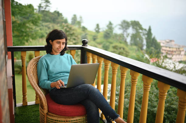 istock Woman using laptop while sitting in a balcony with a scenic view outside 1408423663