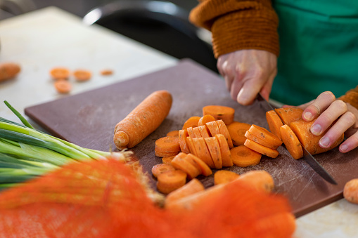 Close up of a volunteer working in a soup kitchen/food bank, chopping carrots and preparing food in the North East of England.