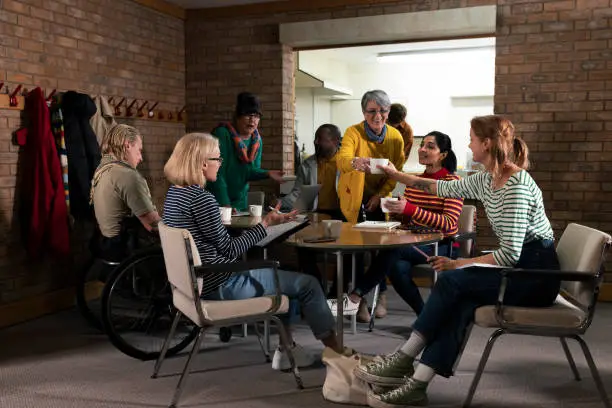 Group of volunteers hosting a meeting about their community in the North East of England. They are a diverse group and are all talking together, organising community events.