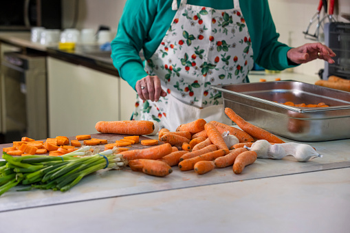 Unrecognisable volunteer working in a soup kitchen/food bank, chopping carrots and preparing food in the North East of England.