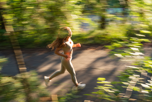 Blurred motion of woman running in public park