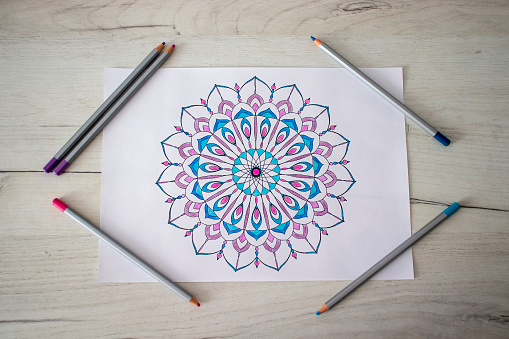 The painted Mandala with pencils lies on the table