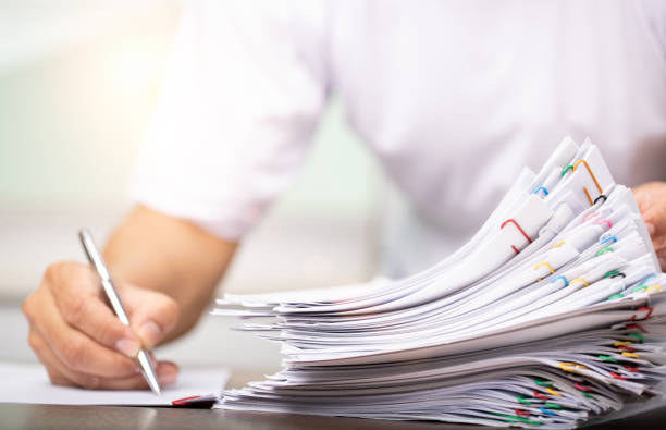istock Man in a white shirt sign contract agreement documents in Stack of Group report papers clipped in color clips in fair light, business, legal law and education concept 1408441828