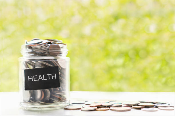 유리 항아리와 녹색 보케 배경의 흰색 테이블에 동전을 닫습니다. 의료 건강 관리, 저축 및 투자 개념을위한 돈을 모으십시오. 플랫 레이 - coin cheap jar currency 뉴스 사진 이미지